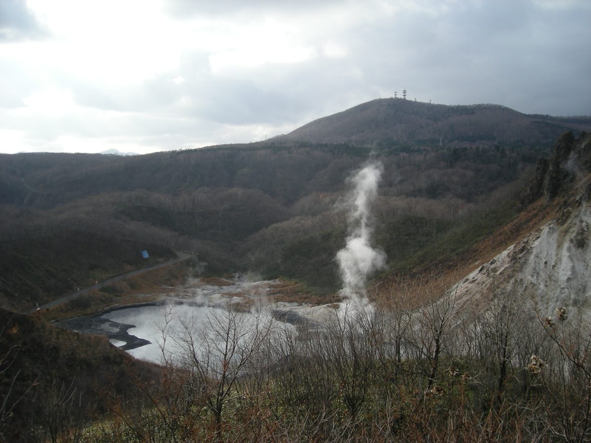 Oyunuma pond in Noboribetsu with a column of steam and wooded hills