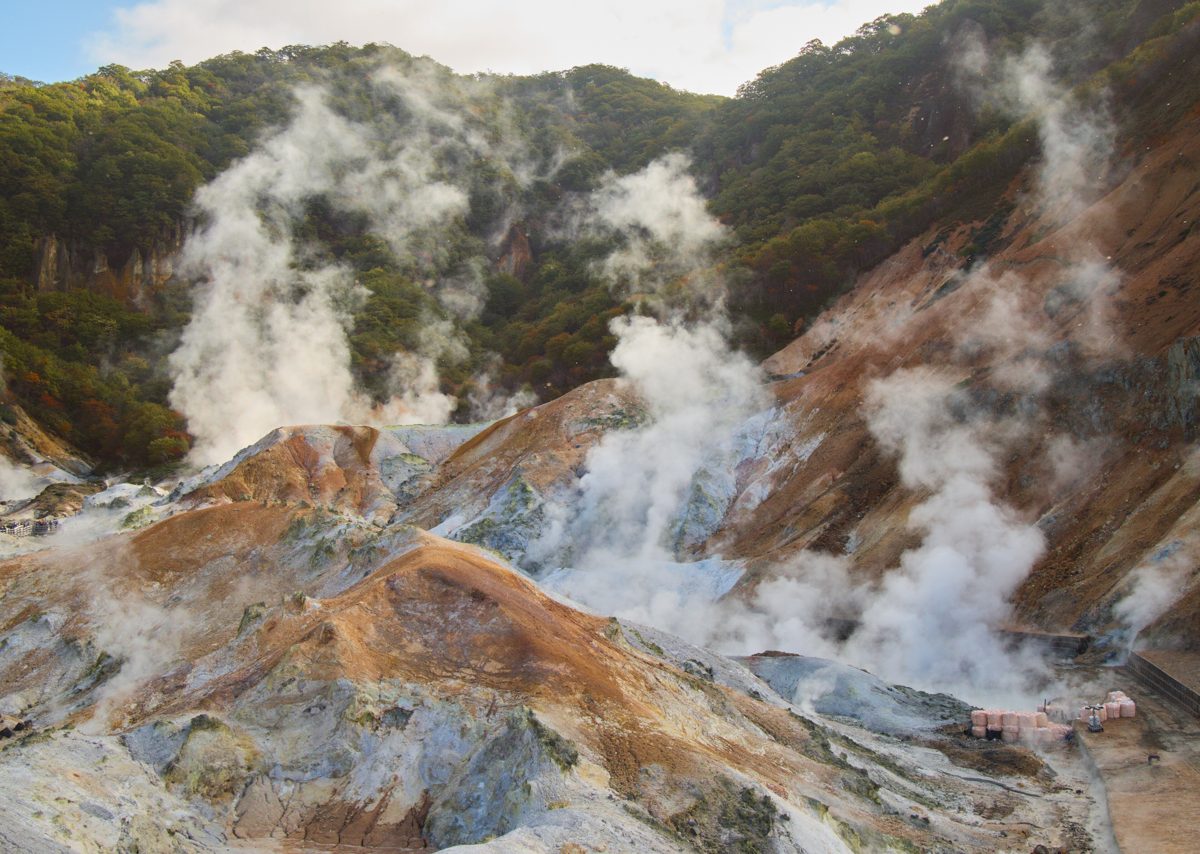 Several steam vents on bare orange and gray ground in Noboribetsu
