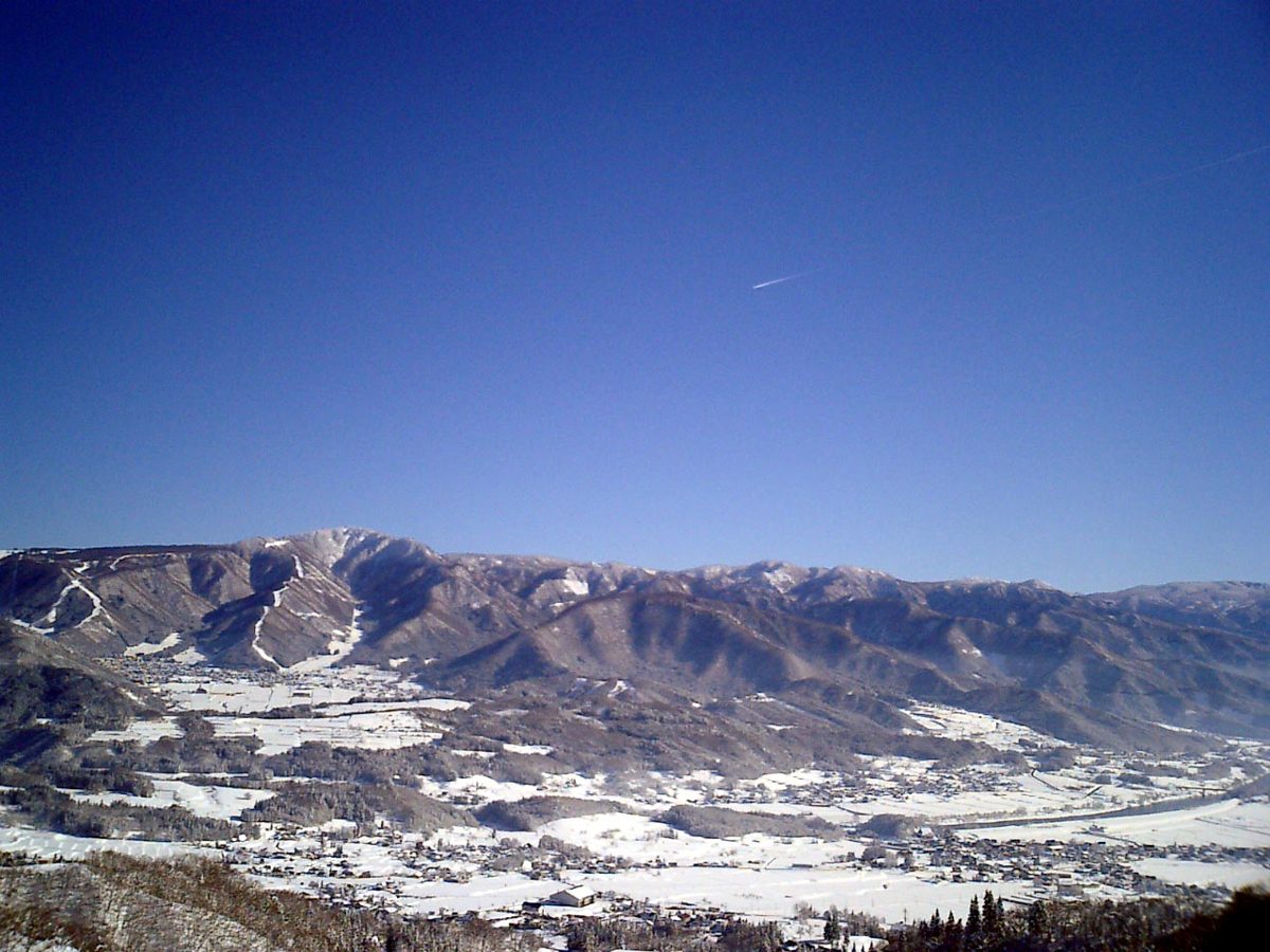 Snowy mountains and valley under a clear blue sky, seen from the west