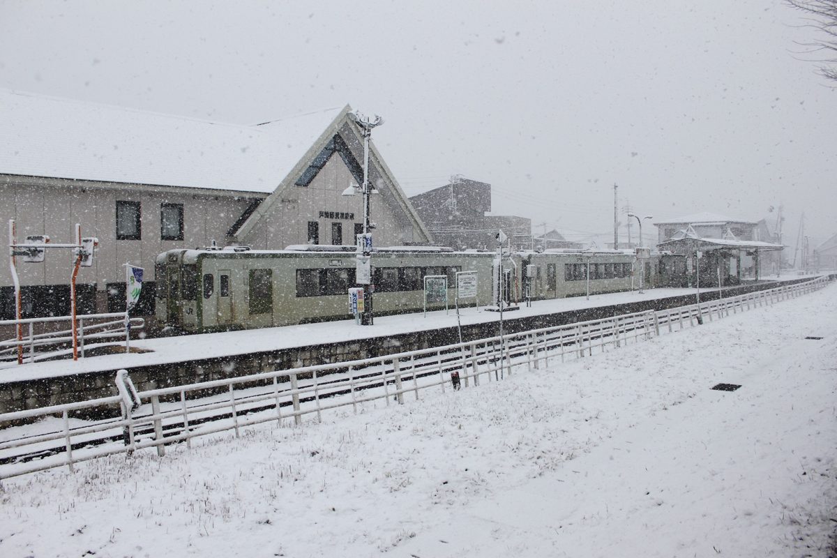 A local train at a snow-covered station during heavy snowfall