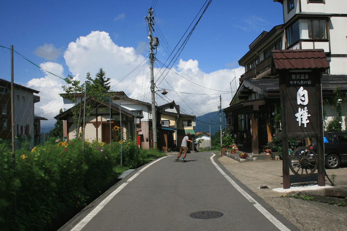 A quiet sloping street lined with wooden inns and houses in summer