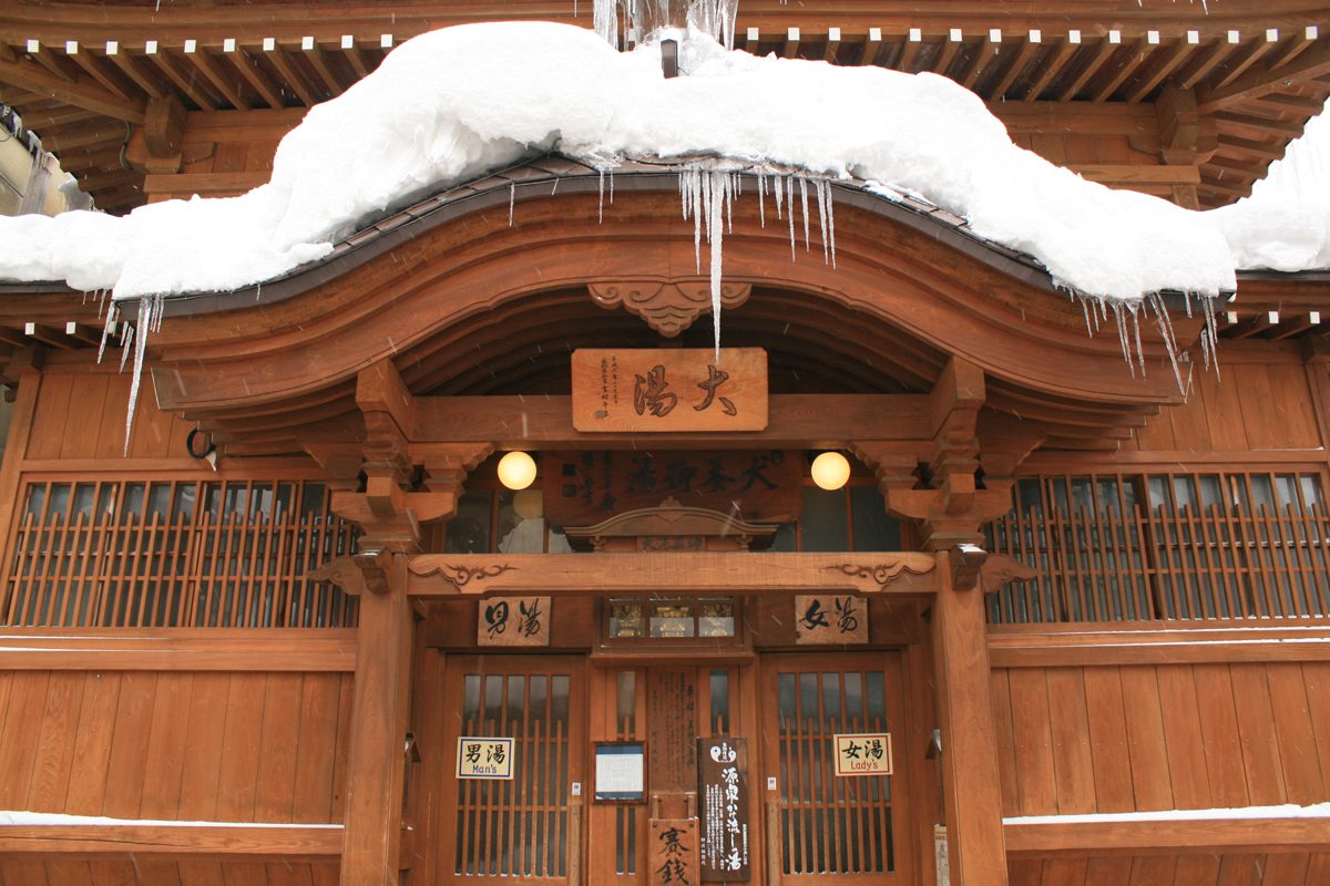 Wooden public bathhouse with snow and icicles on its roof