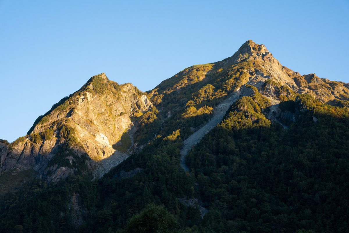 Mountain ridge lit by morning sun under a clear blue sky