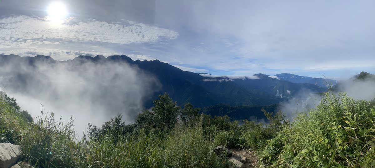 Green mountain slopes and drifting clouds seen from a trail