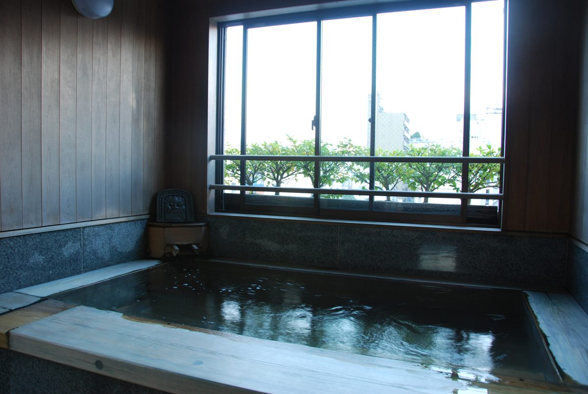 An indoor bath with a large window looking out on trees