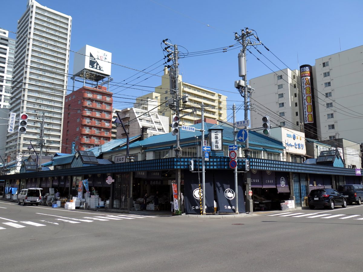 Low market buildings with blue roofs on a city street corner