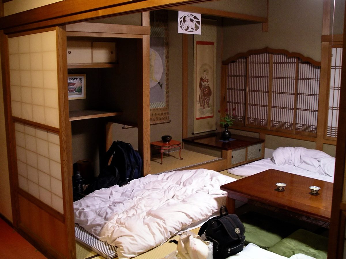 Futons laid out on a tatami floor beside a low table and paper sliding doors