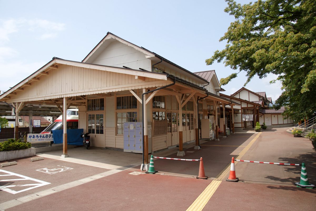 A wooden station building with a paved forecourt under a clear sky