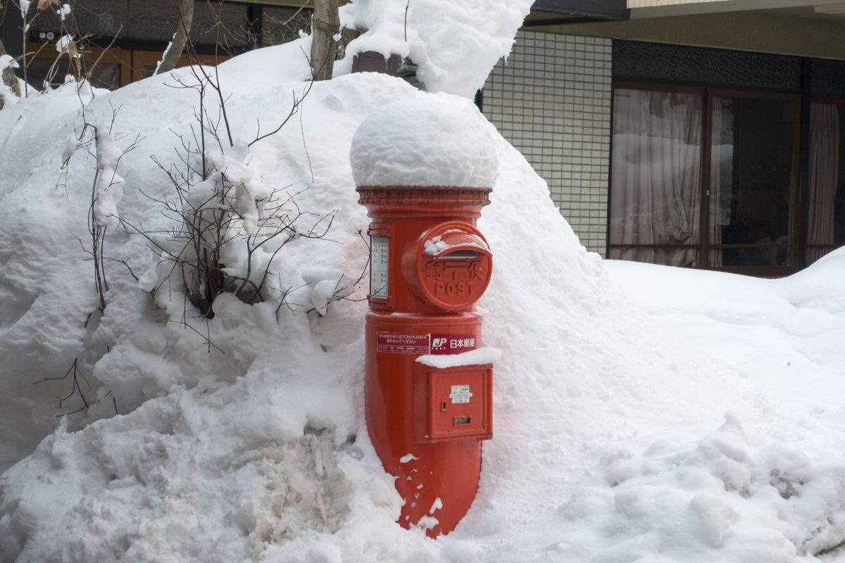 A round red post box half buried in snow