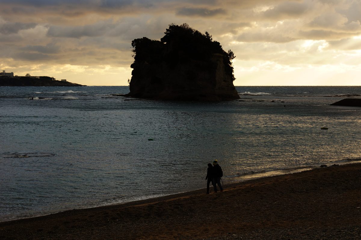 Engetsu Island rock rising from the sea under evening clouds, seen from the shore