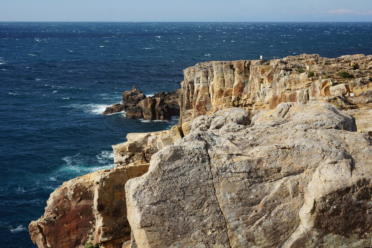Pale rock cliffs dropping into a deep blue sea at Sandanbeki
