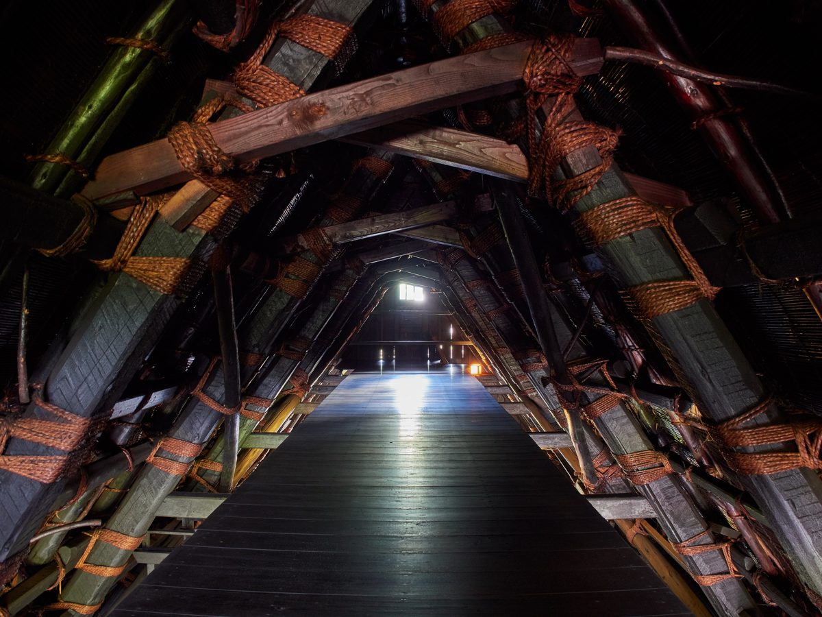 The attic of a gassho-zukuri house, with rope-tied wooden roof beams over a plank floor