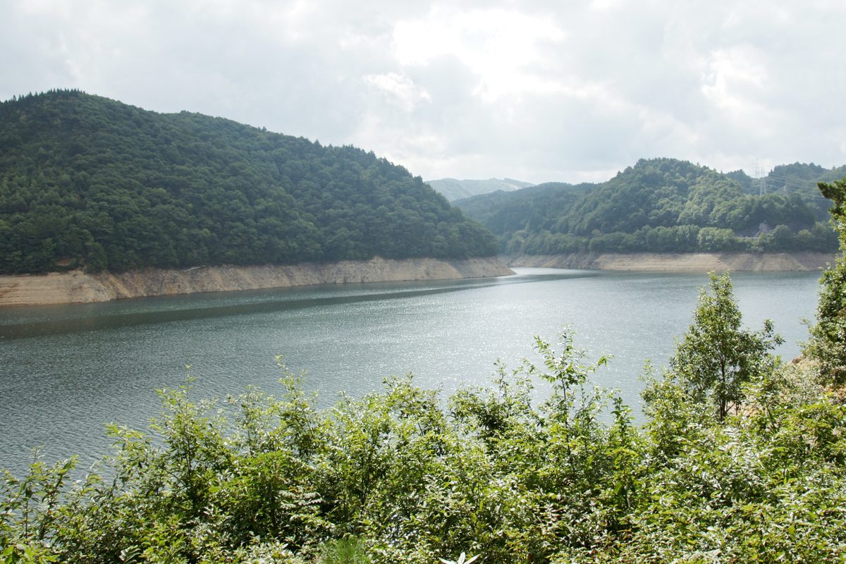 Lake Miboro, a reservoir surrounded by green forested hills, on a cloudy summer day