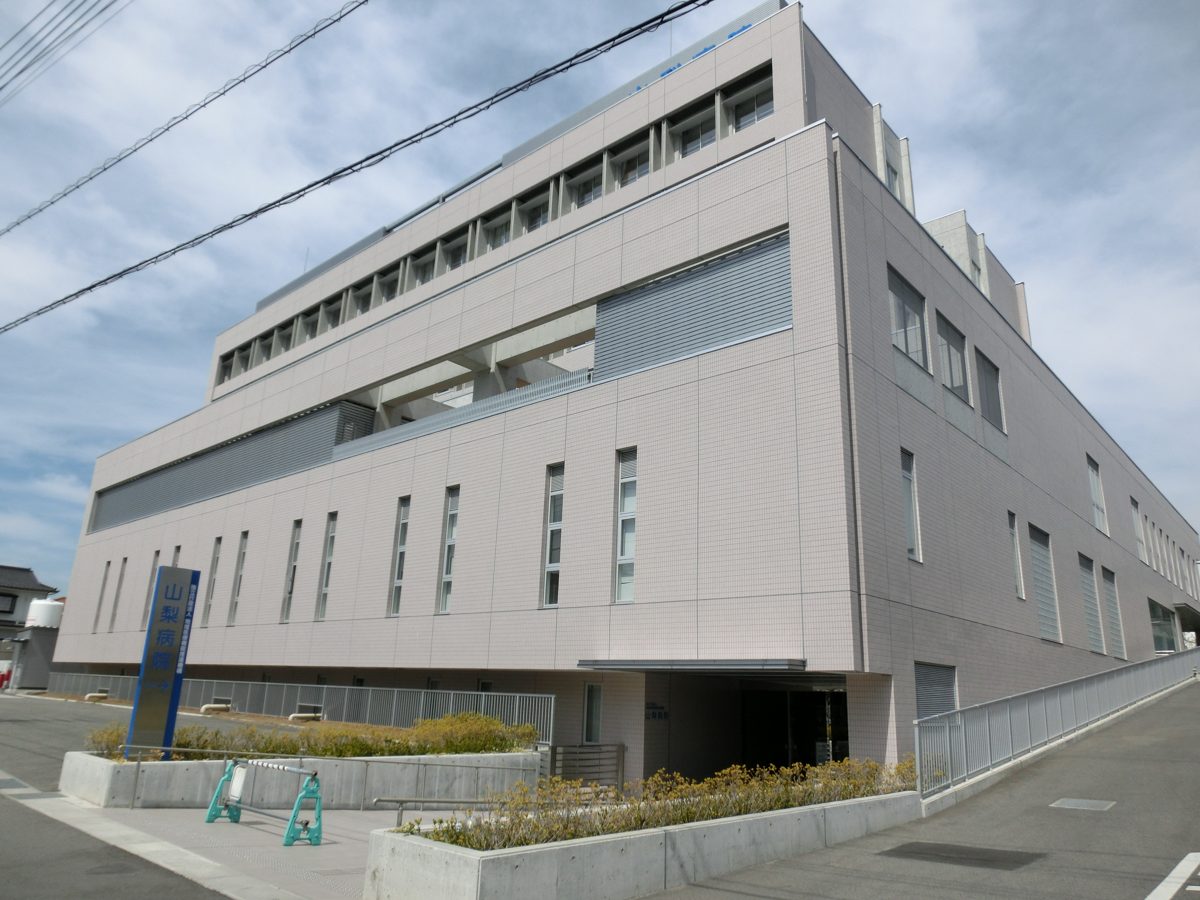 The exterior of a modern multi-story hospital building under a blue sky