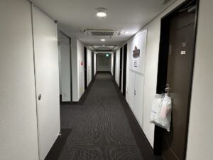 A long carpeted guest-floor corridor with room doors in a Japanese business hotel