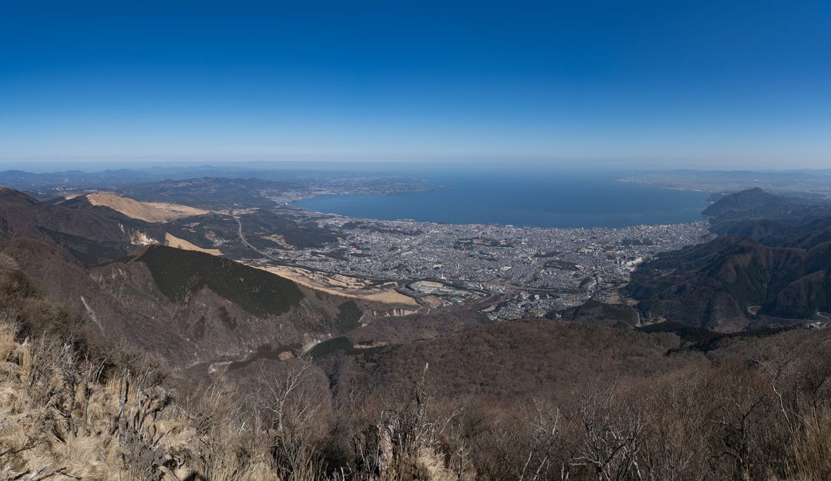 A city spread along a bay, seen from a bare mountainside