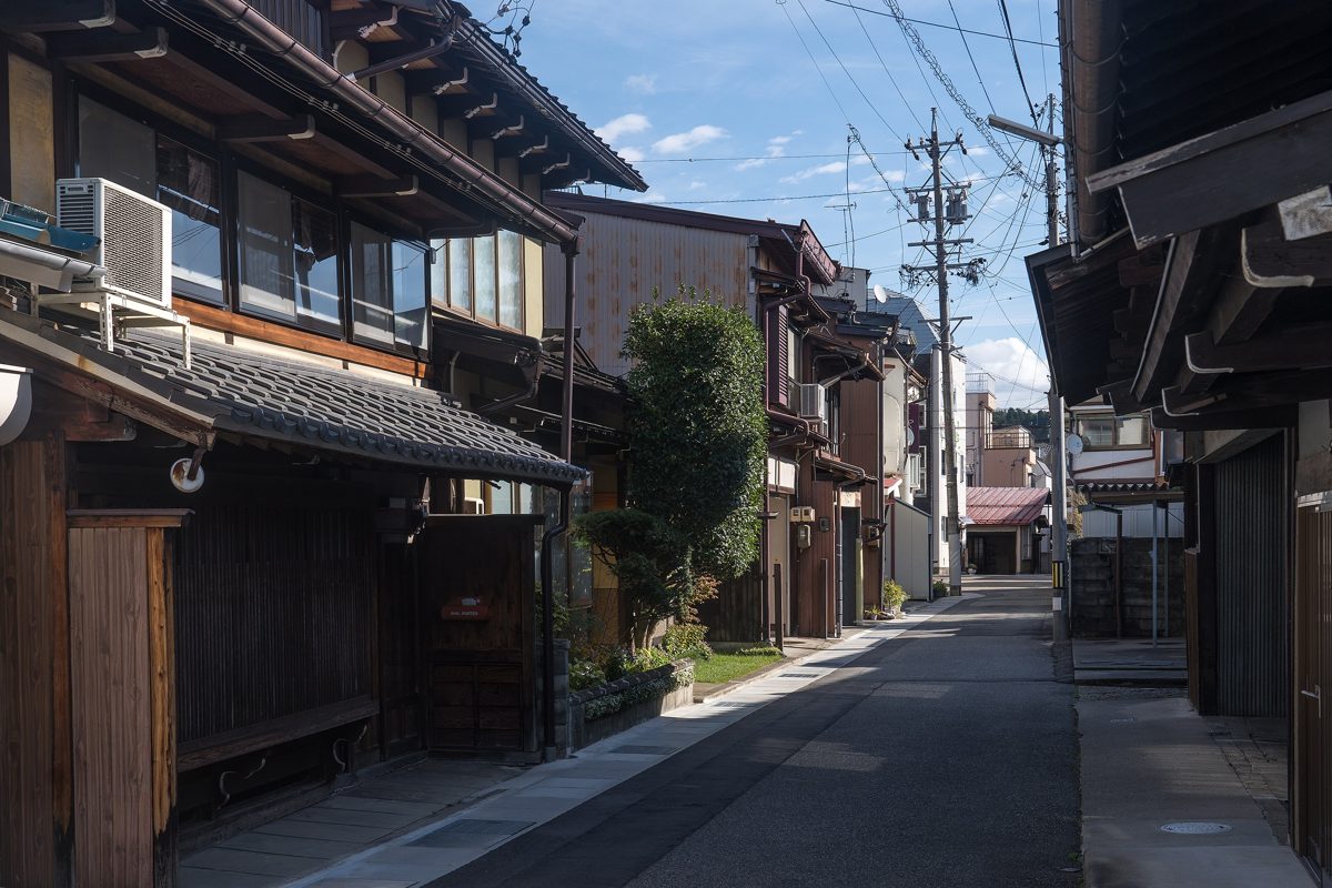 A quiet street of traditional wooden houses under a blue sky in Takayama