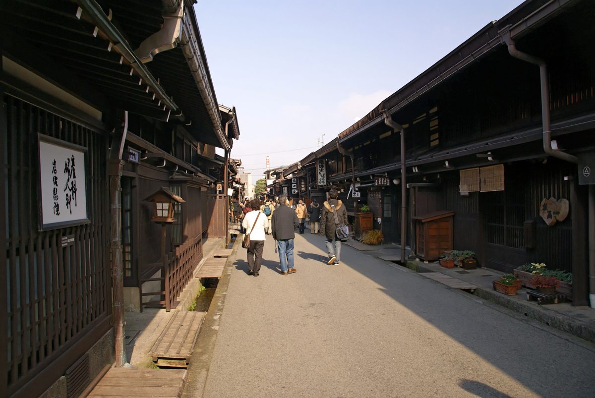 A street of dark wooden merchant houses in Sanmachi, the old town of Takayama, on a sunny day