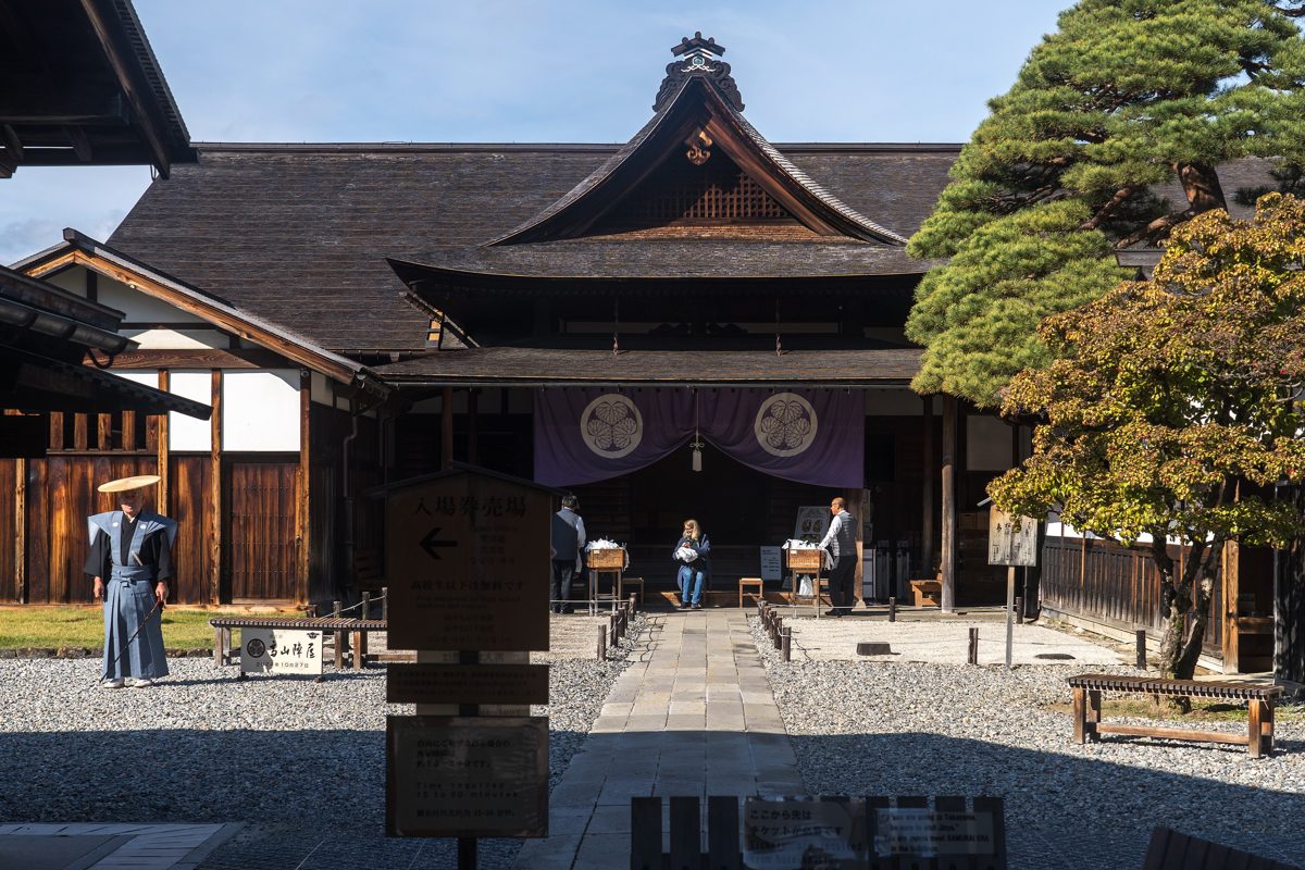 The wooden gate and courtyard of a historic government house under a blue sky