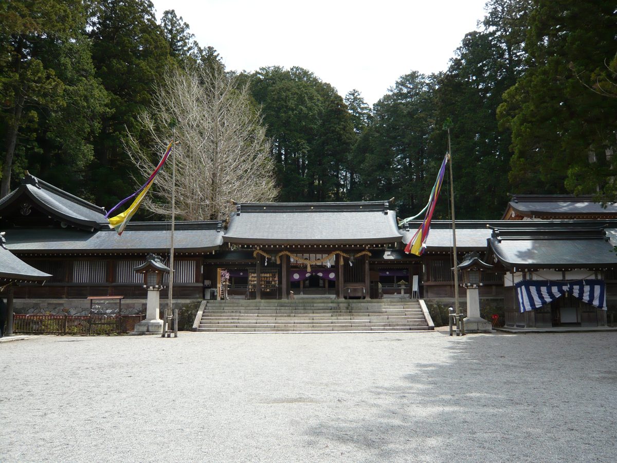 The grounds of Minashi Shrine in Hida-Ichinomiya, Takayama, with tall cedars behind the shrine buildings on a clear day
