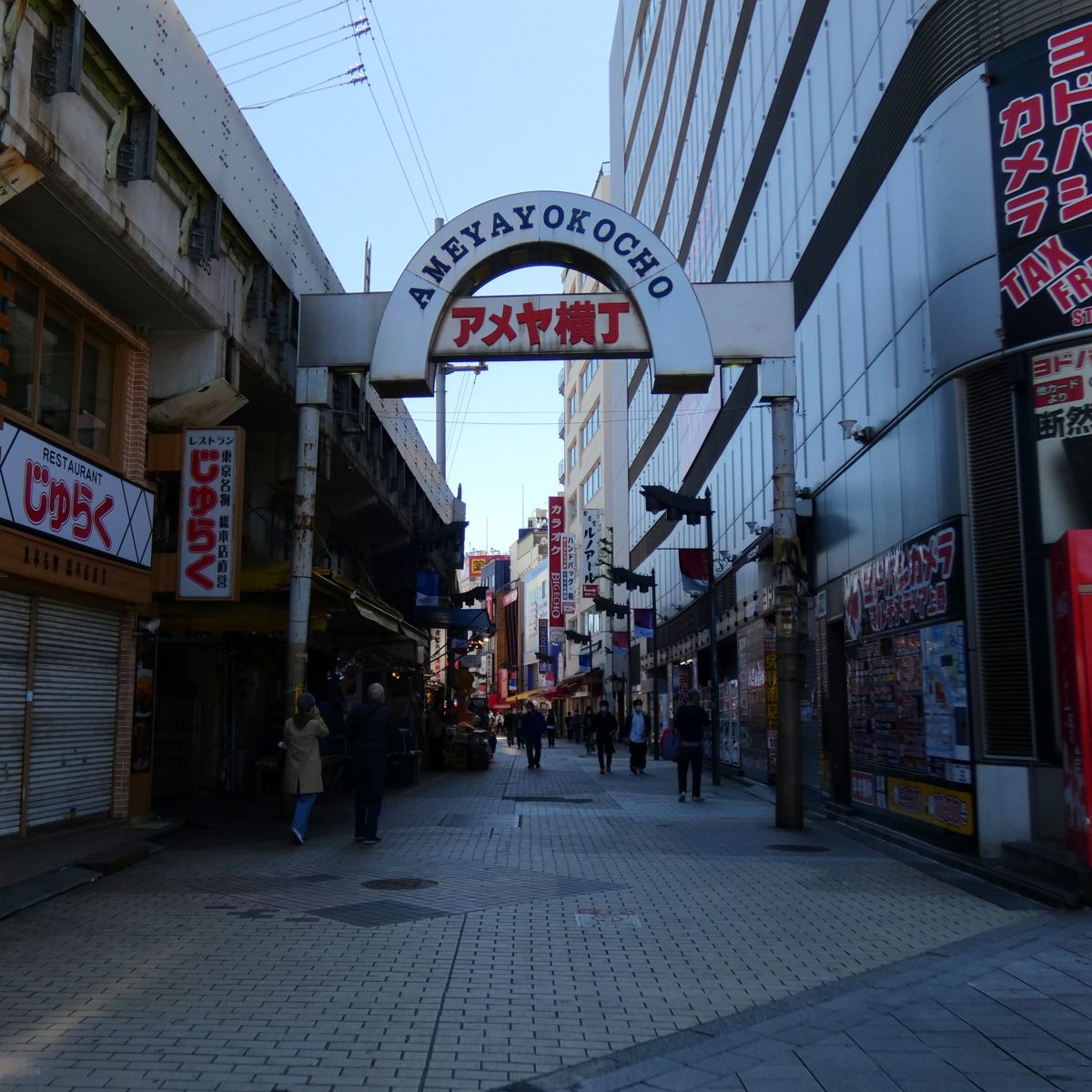 A shopping street entrance arch reading Ameya Yokocho under a blue sky