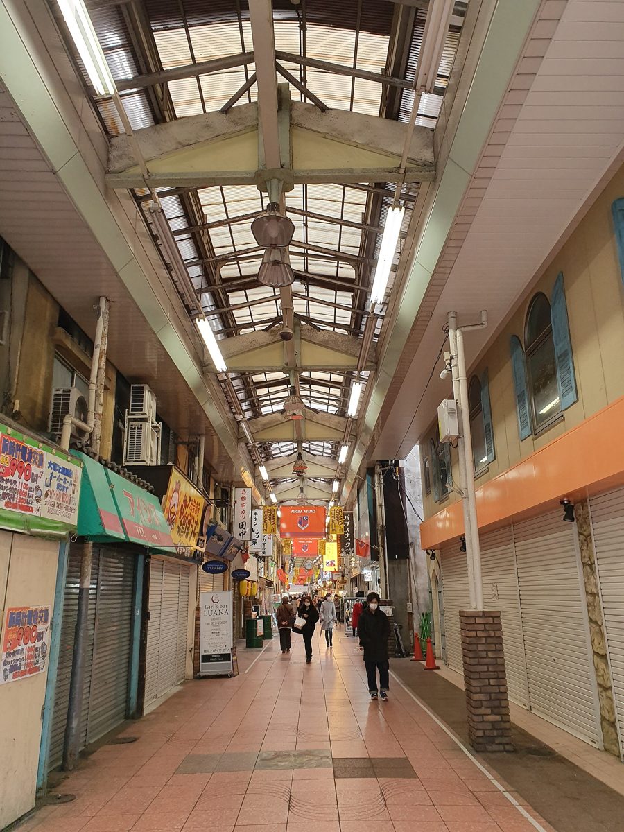 A narrow covered shopping street with closed shutters