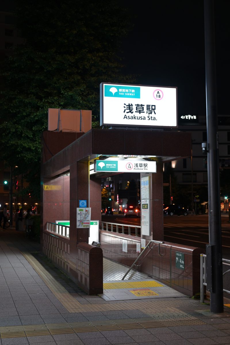 A lit Toei subway entrance with an Asakusa Station sign at night