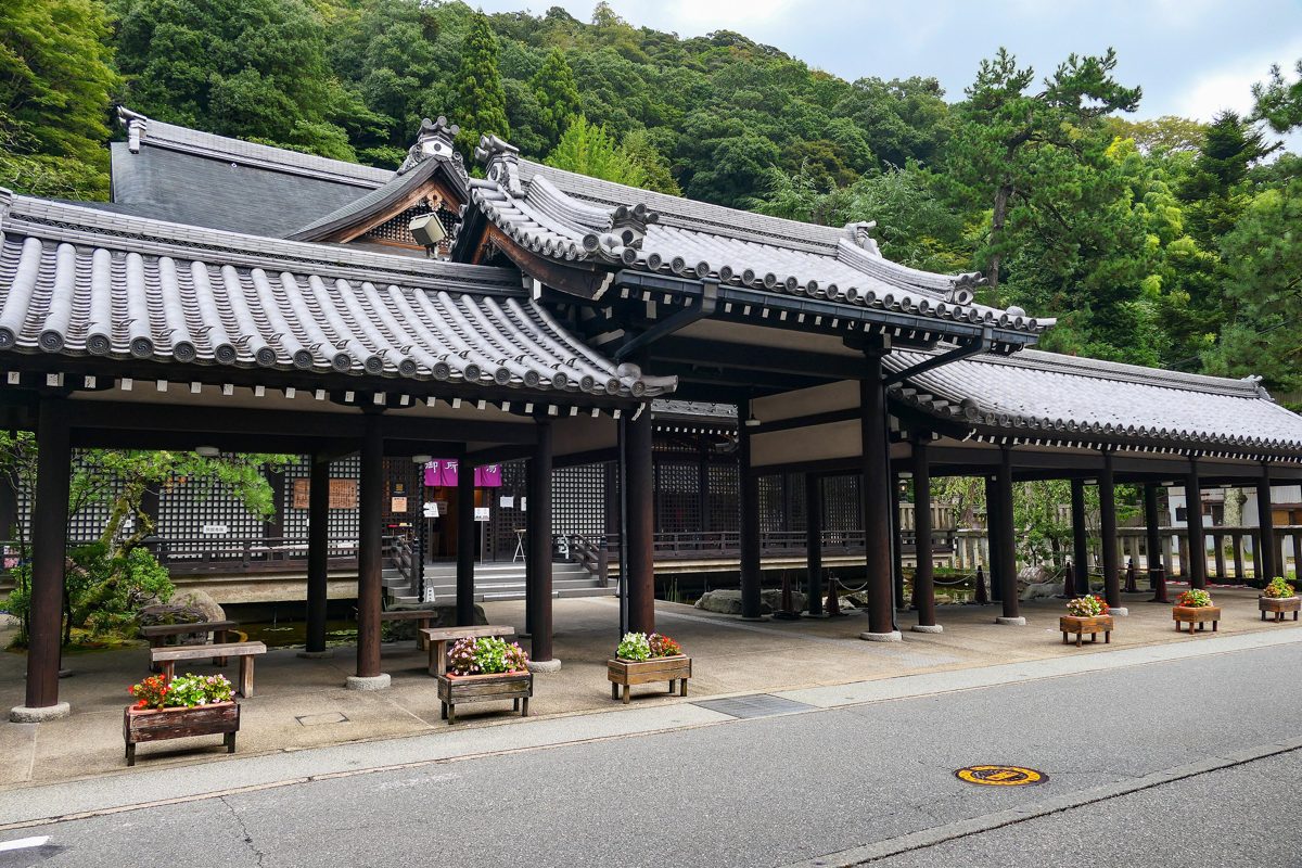 The tiled-roof entrance building of Gosho-no-yu public bathhouse with planters out front