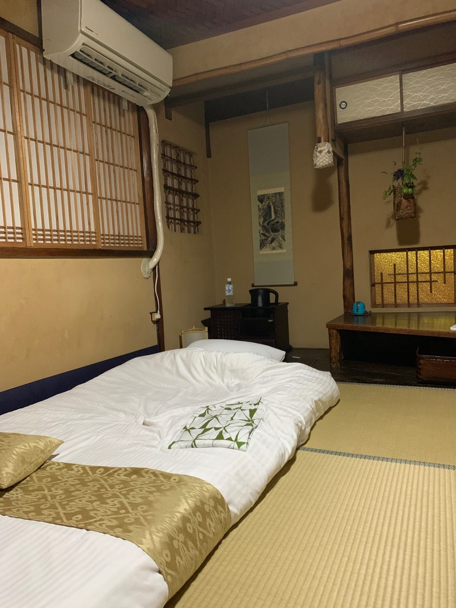 Tatami guest room with a futon laid out, shoji windows and a low table