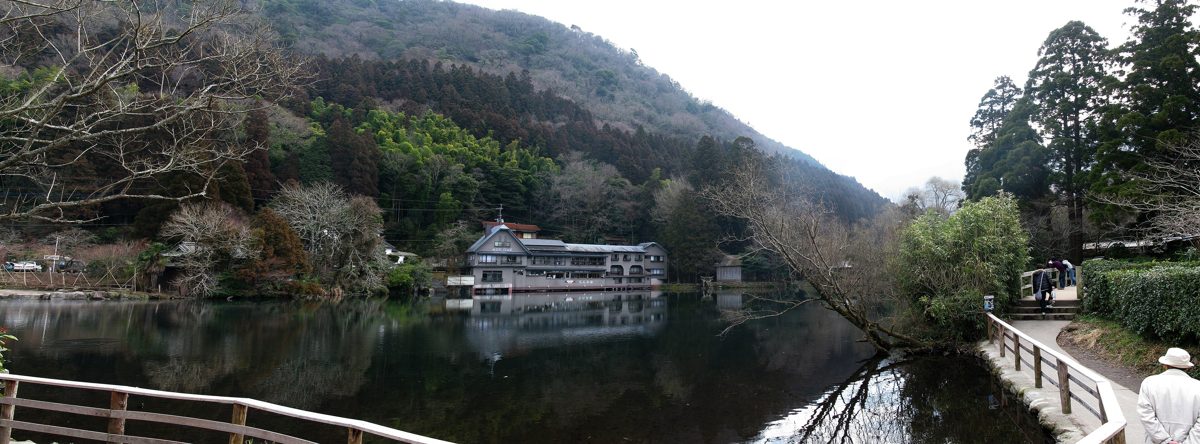 Lake Kinrinko surrounded by trees and hills, with buildings reflected in the water