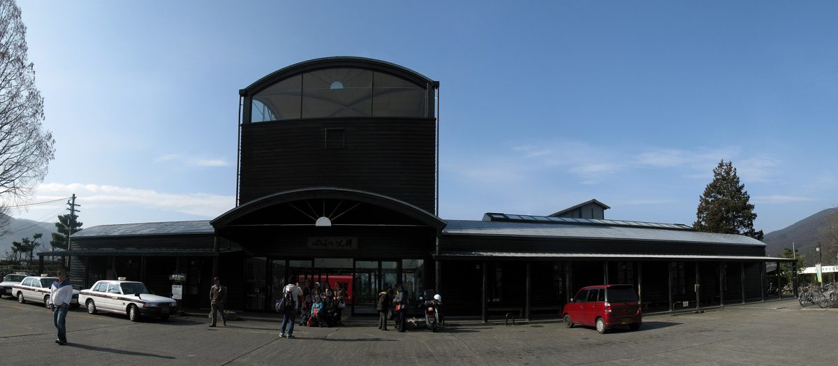 Wide view of the black station building of JR Yufuin Station on a sunny day