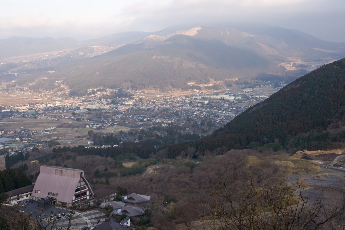 View over the Yufuin basin from a hillside, with the town spread below and mountains behind