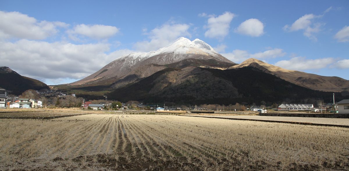 Snow-capped Mount Yufu rising above flat farm fields under a blue sky