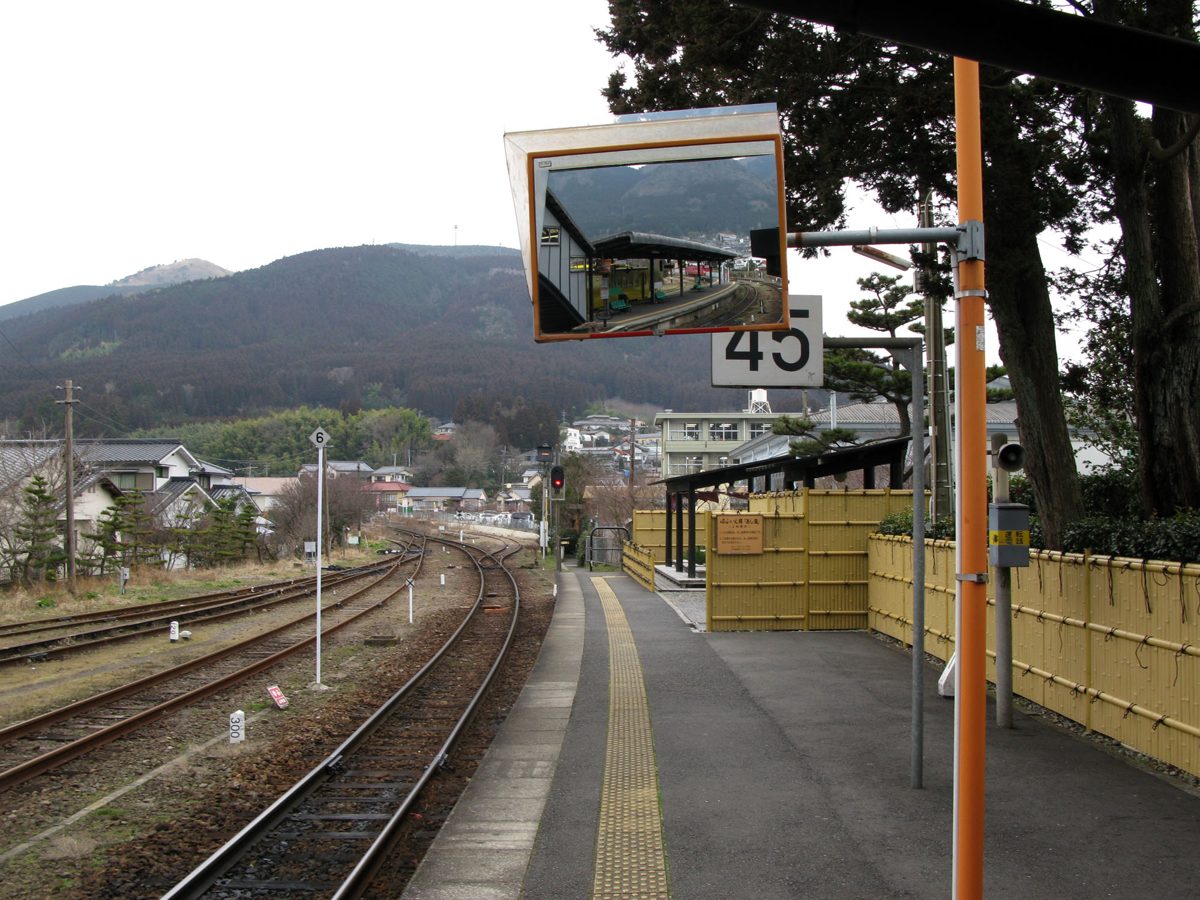 A platform at Yufuin Station on the Kyudai Line, with tracks and mountains in the distance