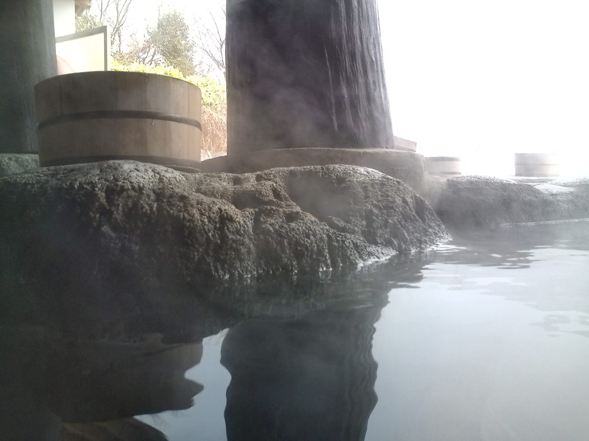 Steam rising from a rock-lined open-air hot-spring bath