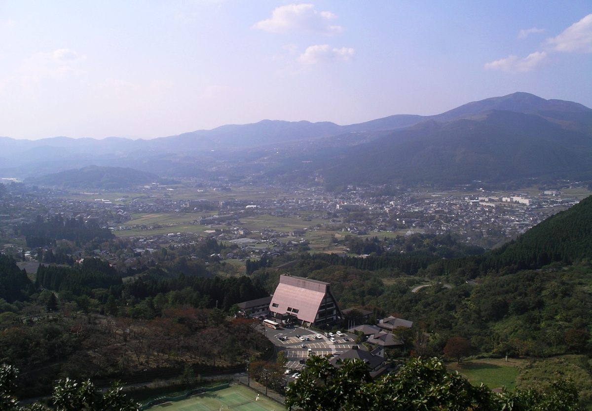 Yufuin town spread across a green basin, seen from a wooded hillside