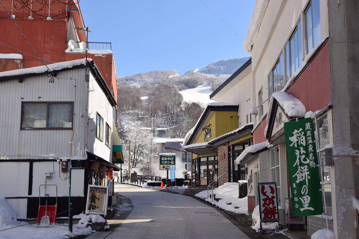 A narrow street of shops and inns in Zao Onsen with snow on the roofs